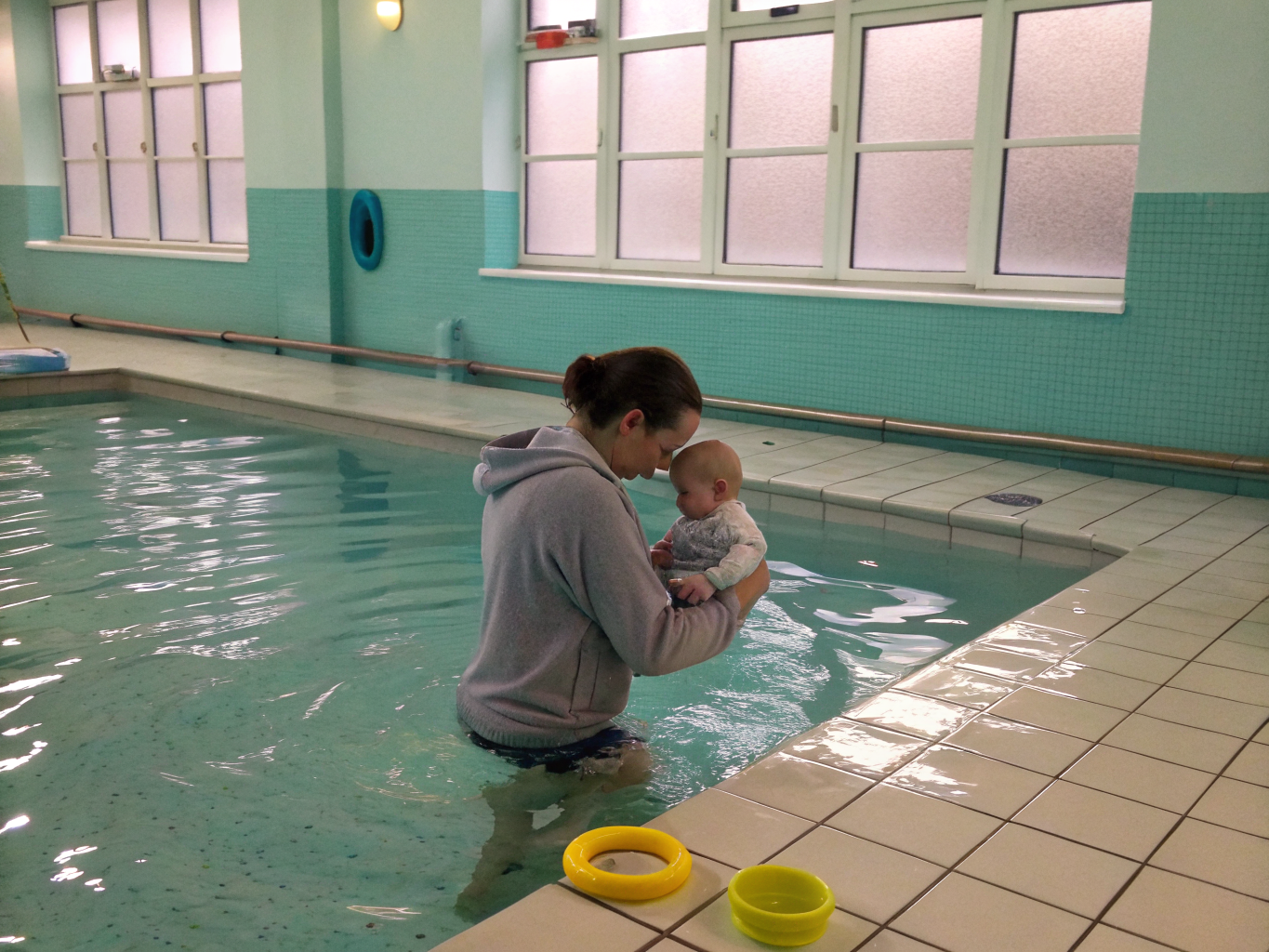 Parent and infant gently splashing together in warm pool